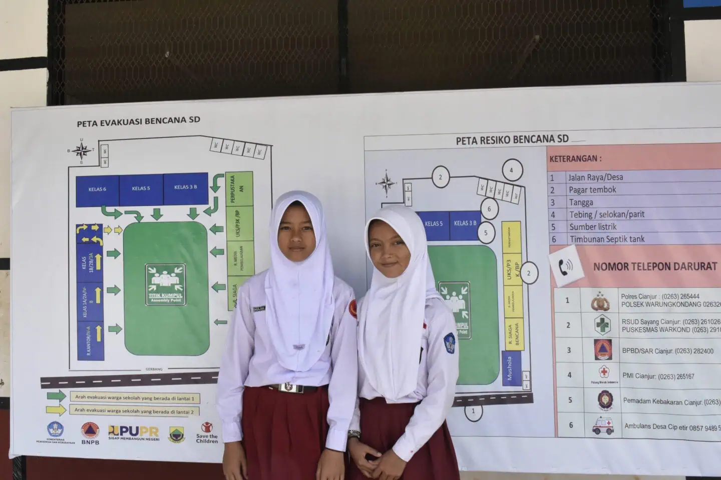Bunga dan Wulan di depan peta evakuasi dan risiko bencana di sekolah